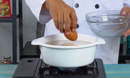 Seorang chef tengah merebus telur untuk resep telur balado.