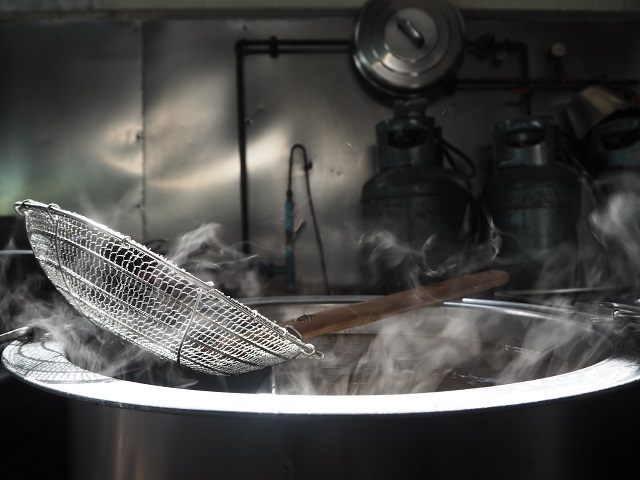 saringan besar di atas panci panas digunakan saat mengolah resep masakan Cina