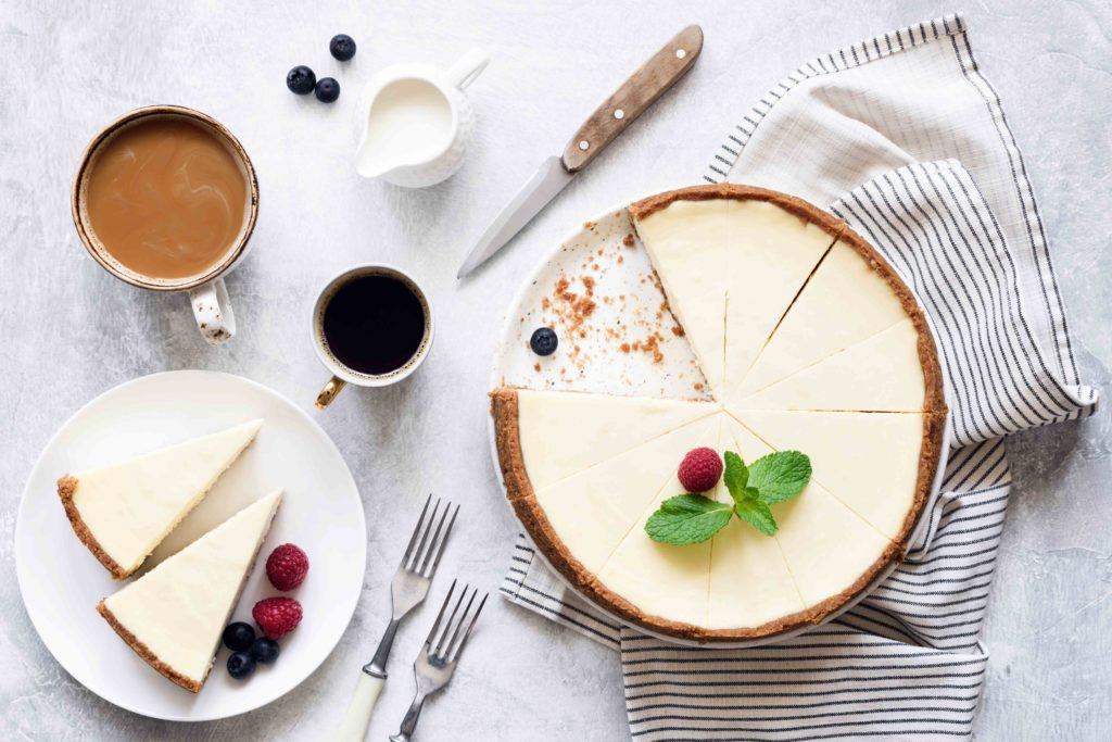 Cheese cake khas Amerika difoto vertikal bersama secangkir kopi.