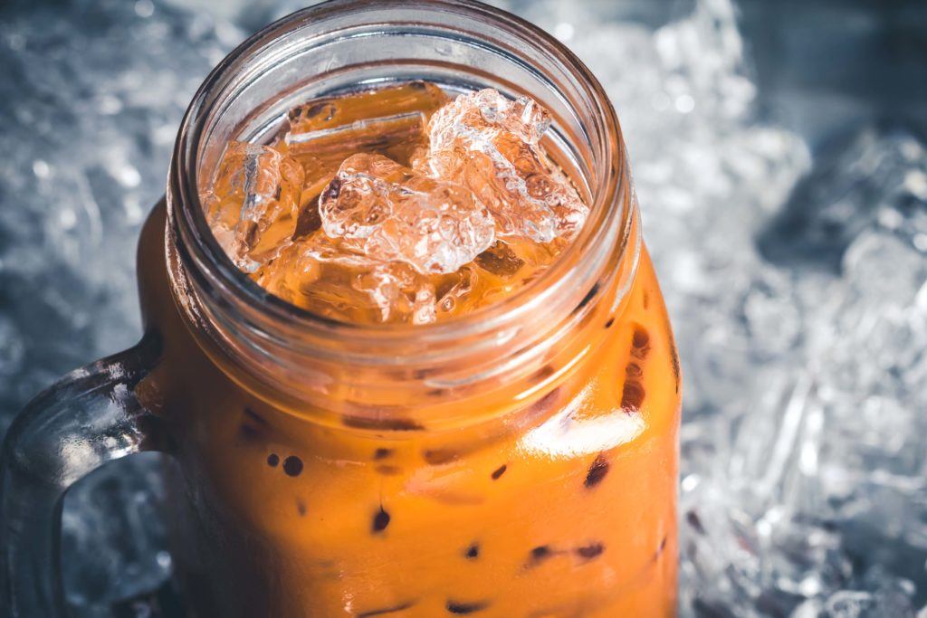 Thai tea dingin dan es batu dalam gelas kaca