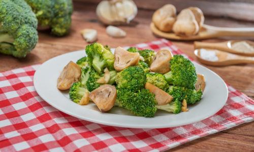 Brokoli saus jamur tersaji di atas piring putih sebagai menu makan siang sederhana.