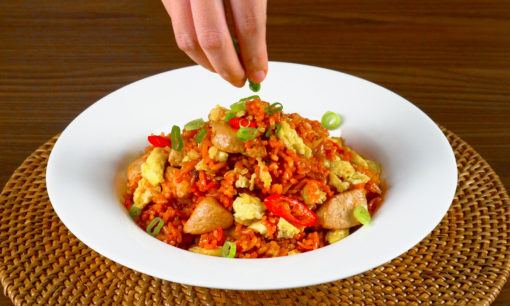 Menyajikan Nasi Goreng Merah dengan taburan bawang goreng.