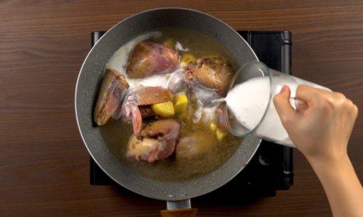 Menuangkan santan untuk memasak ayam kurma.