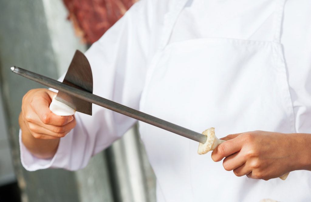 Seorang chef mengasah pisau dengan honing steel