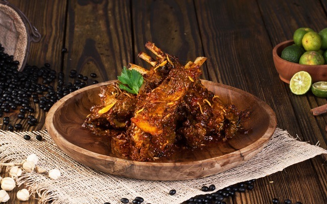 Satu piring makanan khas Gorontalo berupa kambing bakar belanga di atas napkin warna putih.