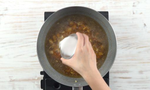 Tepung tapioka dimasukkan ke dalam tumisan daging kecap dalam wajan.