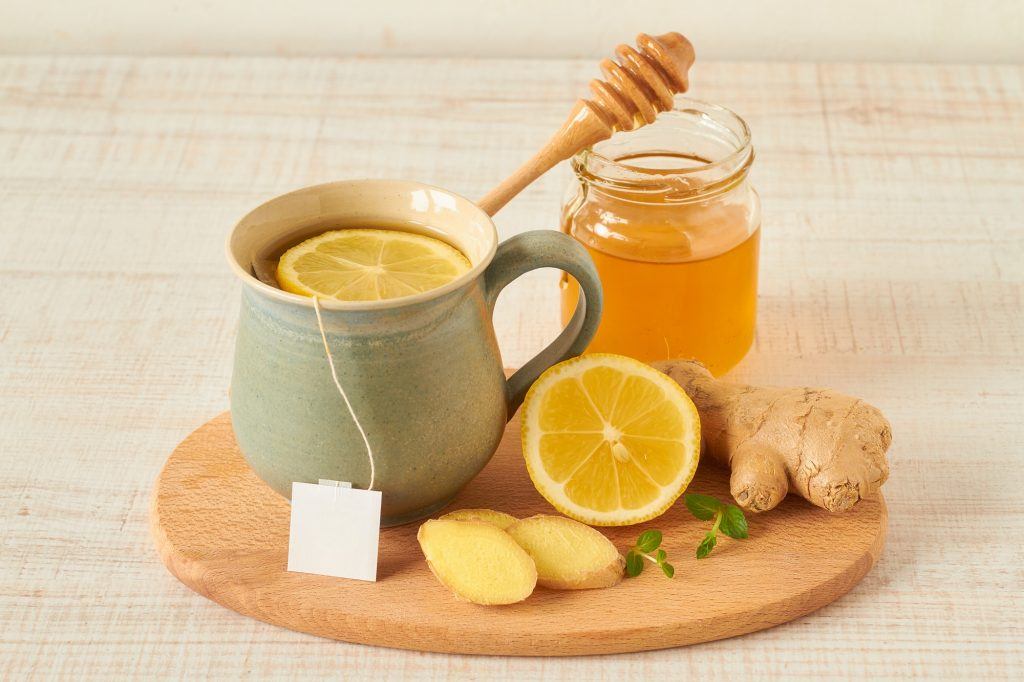 Minuman sehat dalam mug dikelilingi oleh lemon, jahe, madu, untuk mencegah korona.