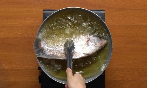 Saat menggoreng pecak ikan gurame, pastikan ikan terendam dengan minyak panas.