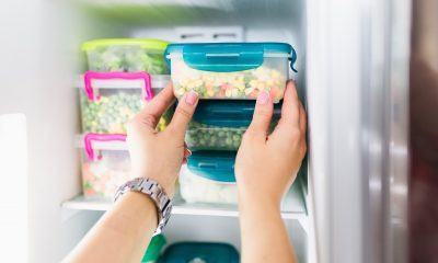 Tangan menyimpan container bahan makanan dalam kulkas.