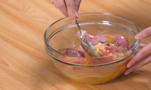 Membumbui ayam goreng krispi agar meresap rasanya dalam mangkuk secara merata.