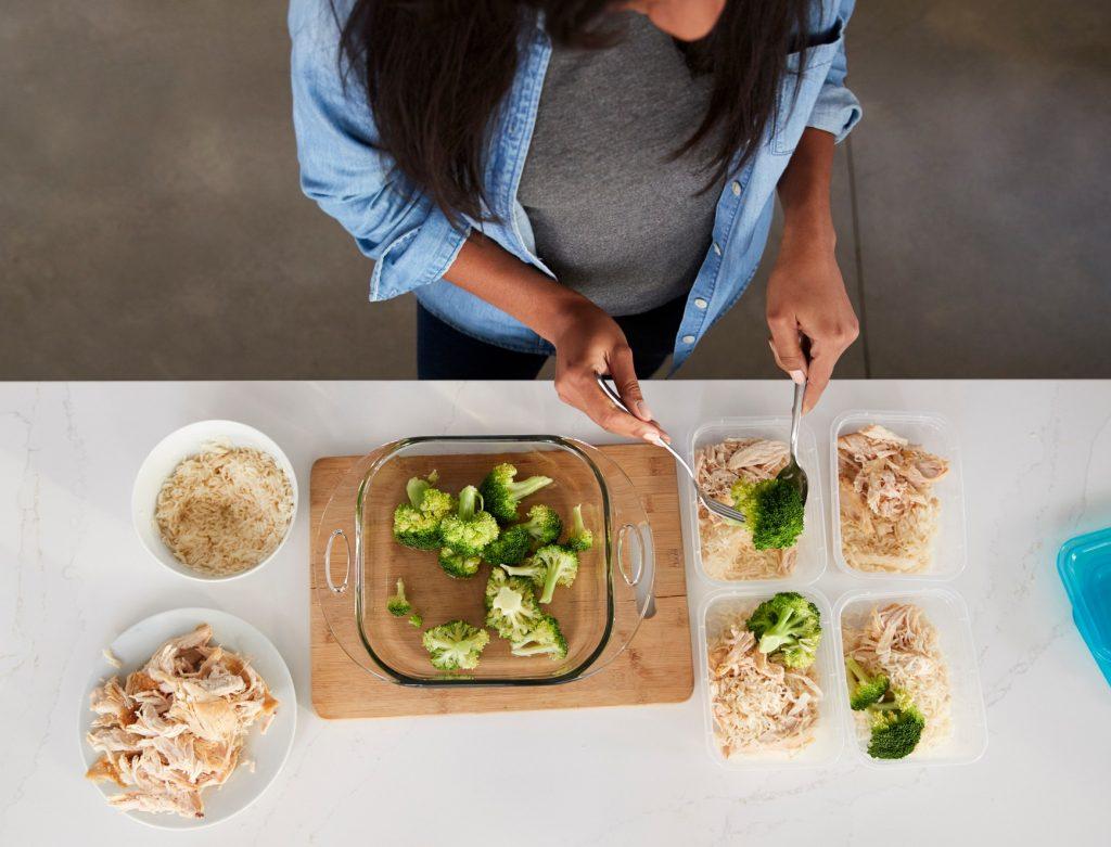 Seorang wanita tengah menyiapkan meal prep di meja dapur