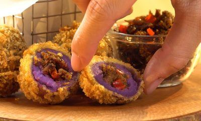 Hasil memasak resep bola ubi ungu tersaji di atas meja kayu dan tengah dinikmati.