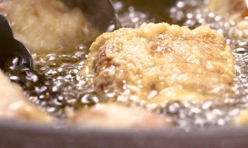 Menggoreng tahu Sumedang dalam wajan berisi minyak banyak dan panas.