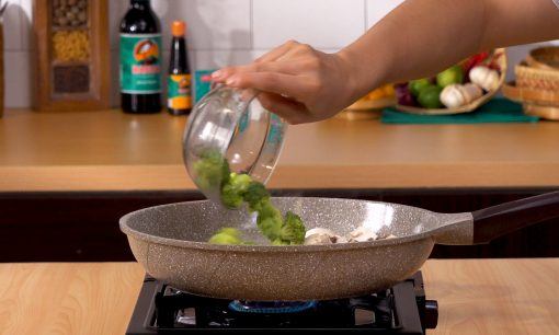 Potongan brokoli dituangkan dimasukkan ke dalam wajan.