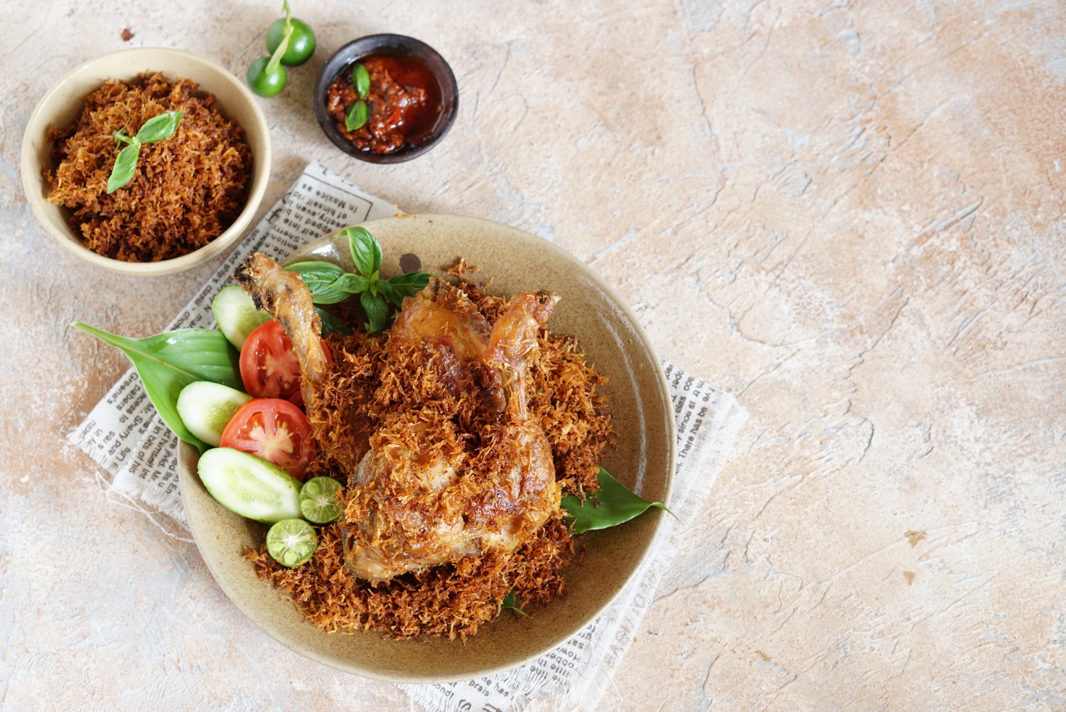 Sepiring kreasi masakan ayam goreng serundeng kelapa bersama sambal di sampingnya.