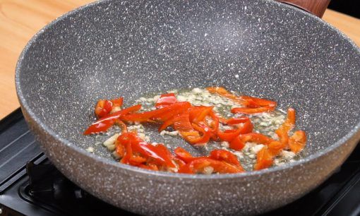 Menumis cabai dan bawang untuk resep nasi goreng ikan asin.