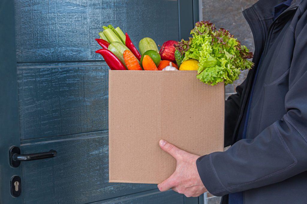 Seorang pria mengantarkan paket sayuran di depan pintu