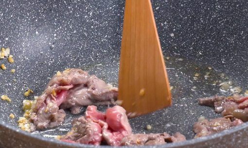 Menumis daging sapi di atas wajan.