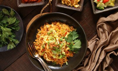 Nasi goreng padang di piring dikeliling piring kecil berisi sambal dan telur.