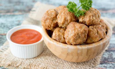 Hasil masak resep bakso goreng disajikan dalam mangkuk kayu dan didampingi saus sambal.