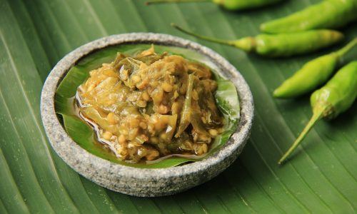 Sambal ijo disajikan dalam cobek mini dan didampingi cabai rawit serta diletakkan di atas daun pisang.