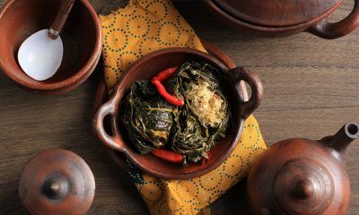 Buntil daun singkong dalam piring tanah liat dengan napkin batik