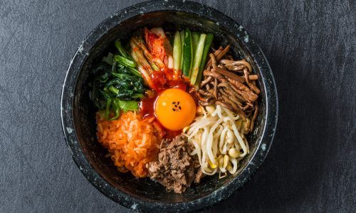 Dolsot bibimbap, makanan khas Korea Selatan dengan topping macam-macam sayuran dan telur disajikan dalam mangkuk batu.