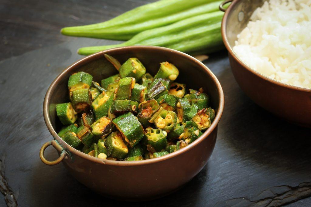 Tumis okra di mangkuk dengan nasi putih di belakangnya.