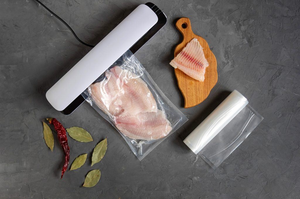 vacuum sealer sedang merapatkan plastik berisi dada ayam mentah