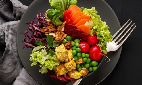 Piring hitam berisi aneka jenis sayuran untuk plant based diet.