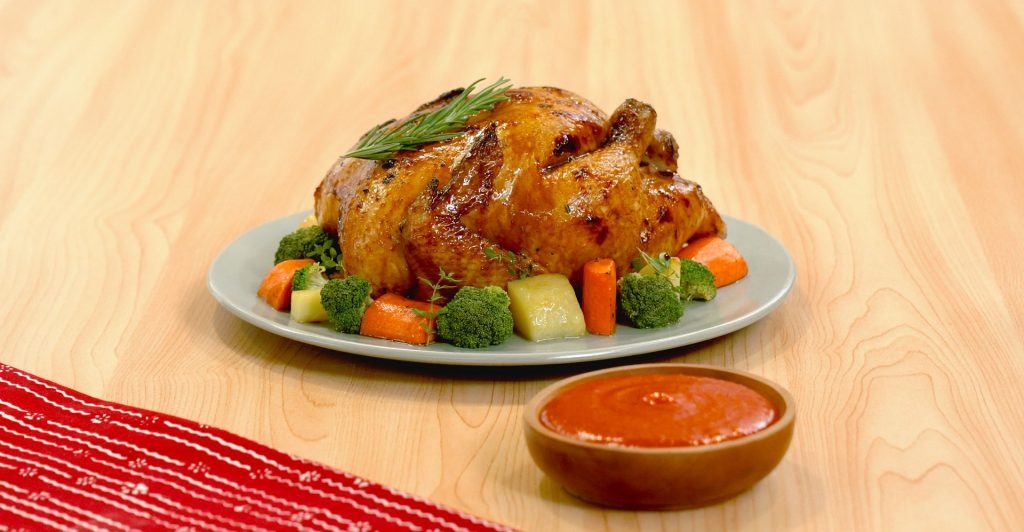 Hampers Natal berupa Ayam panggang yang dikelilingi sayuran serta saus pedas.
