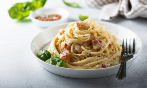 Olahan resep pasta spaghetti carbonara disajikan dalam piring putih.