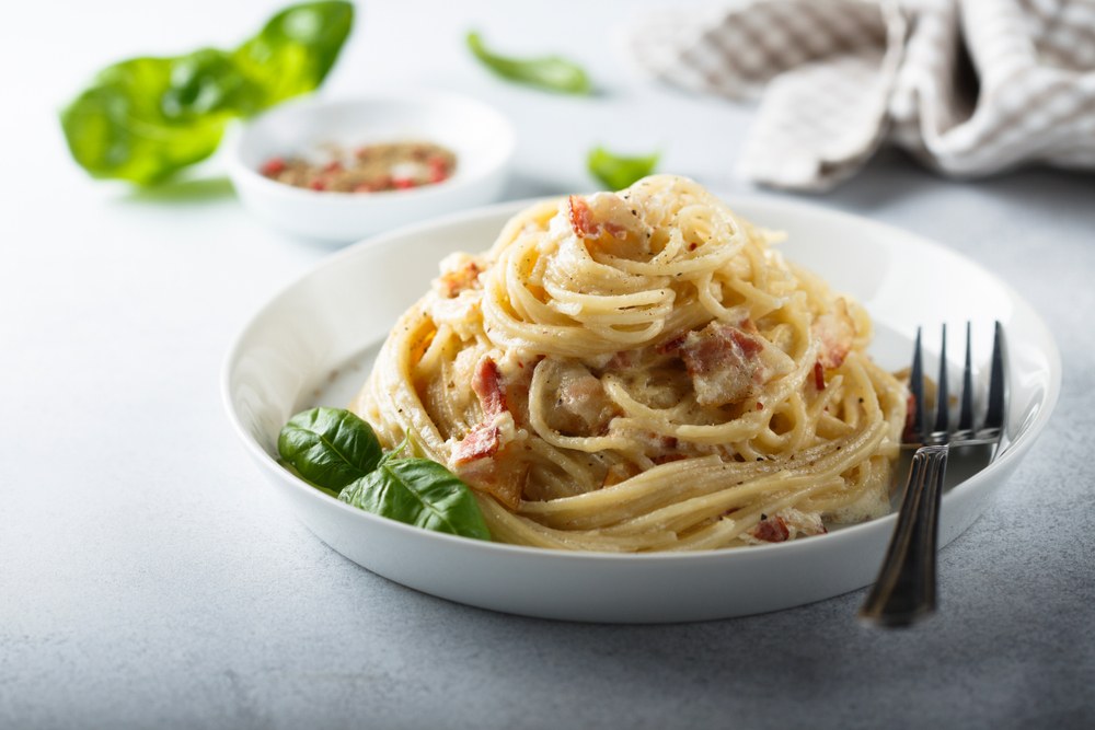 Olahan resep pasta spaghetti carbonara disajikan dalam piring putih.