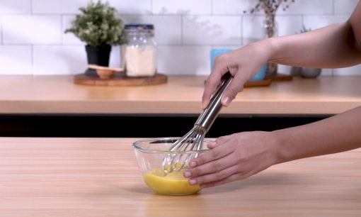 Mengocok telur dengan whisk.