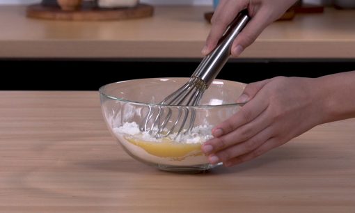 Mengaduk tepung dengan spatula.