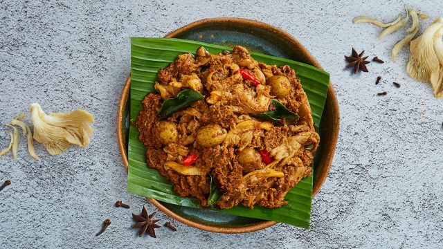 Seporsi besar rendang kentang jamur disajikan di atas meja batu. Olahan kentang untuk lauk.