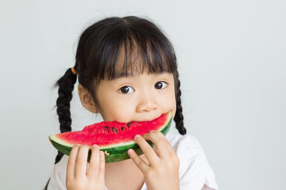 Seorang anak sedang makan buah sebelum makan.