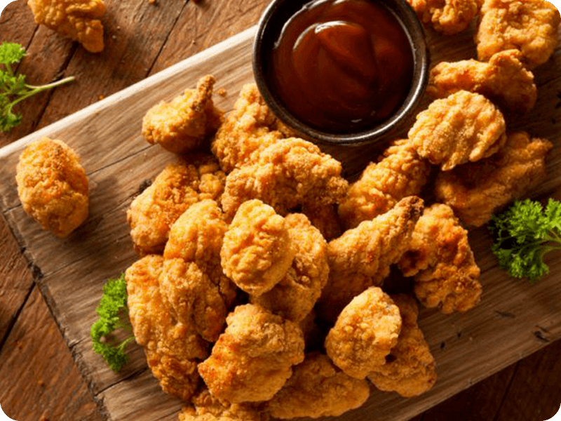 Ayam Popcorn diatas piring kayu bersama semangkuk saus sambal