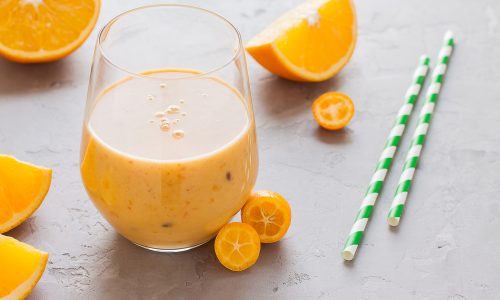Segelas jus buah jeruk dengan sedotan.