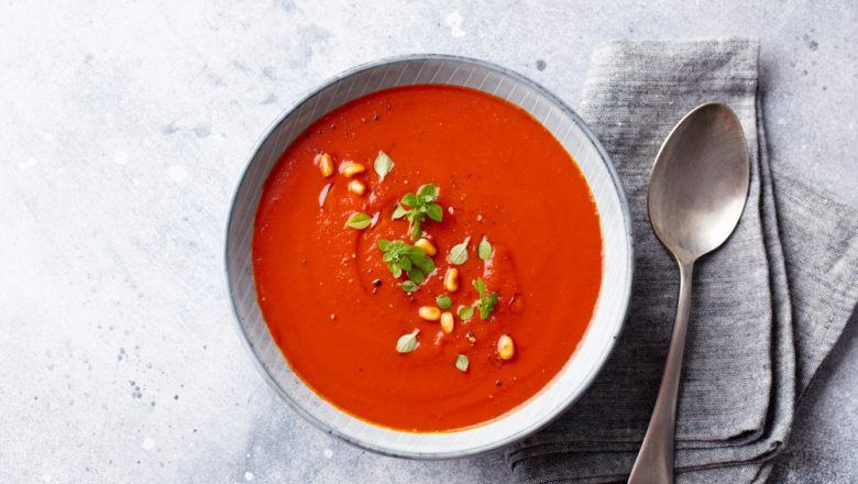 Semangkuk resep sup tomat dan jagung dengan alat makan.