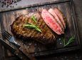 Daging steak dengan tingkat kematangan medium rare disajikan di atas talenan.