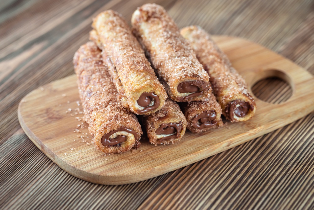 Roti gulung cokelat disajikan di atas talenan.