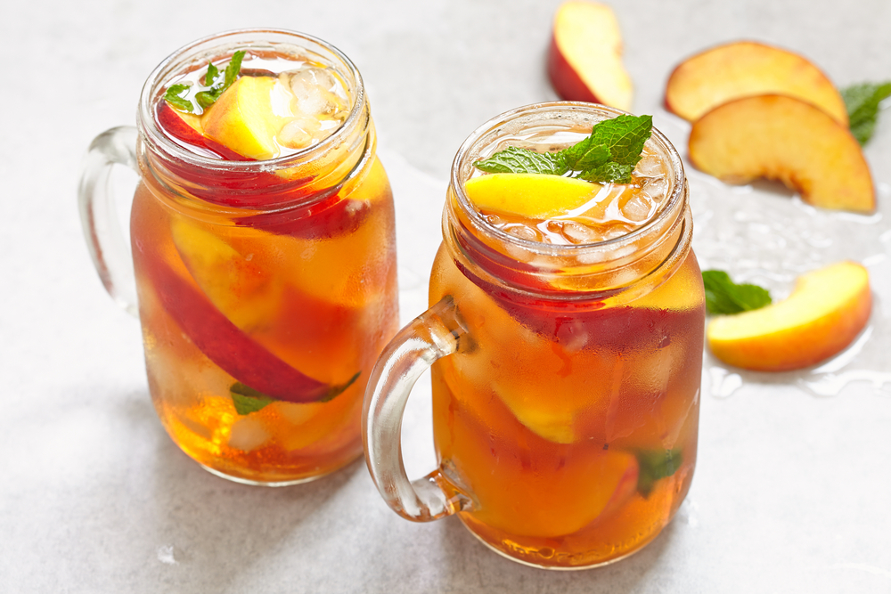 Dua gelas iced peach tea siap dengan topping daun mint.