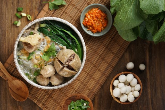 Semangkuk bakso dengan sambal, pilus, dan pelengkap lain.