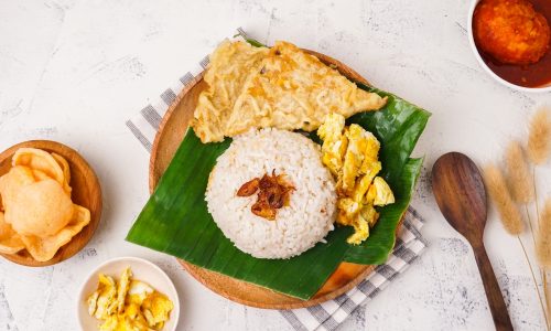 nasi uduk yang dimasak di rice cooker di atas daun pisang dengan telur dan gorengan
