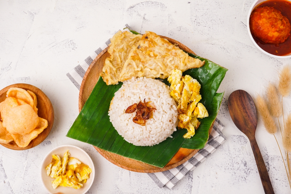 nasi uduk yang dimasak di rice cooker di atas daun pisang dengan telur dan gorengan