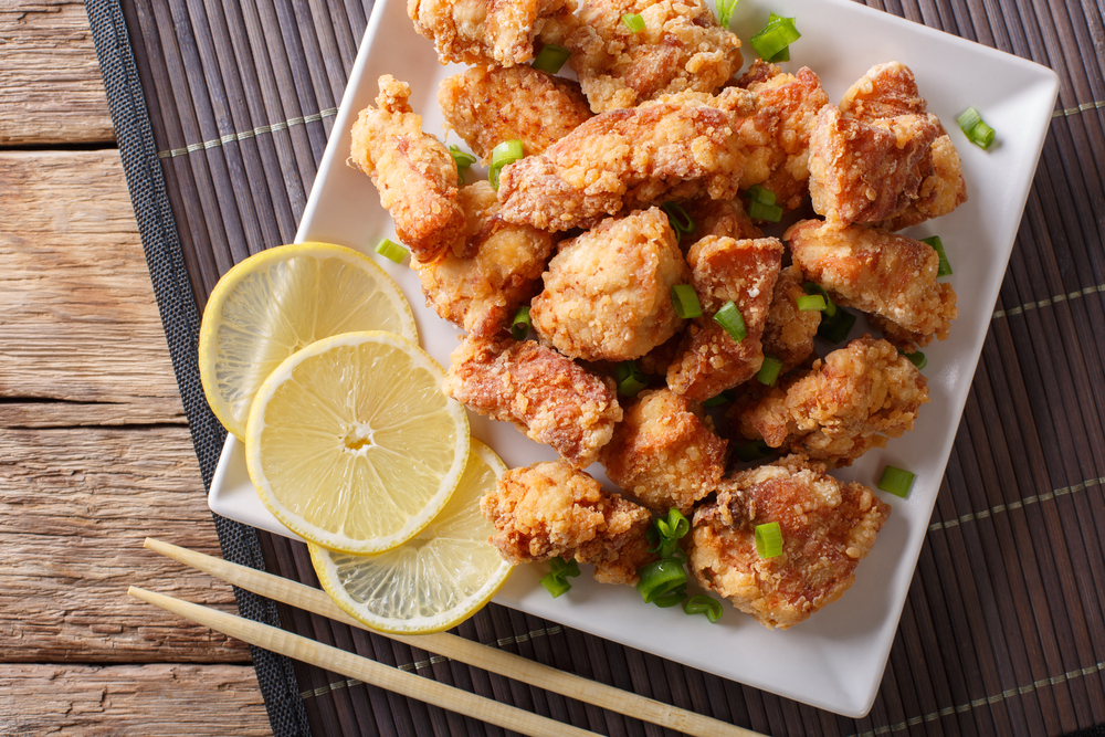 Chicken karage dengan irisan jeruk lemon disajikan di atas piring putih.